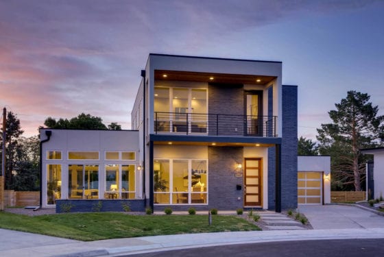 Evening view of the E Bails Drive home with interior lighting glowing through full-height windows